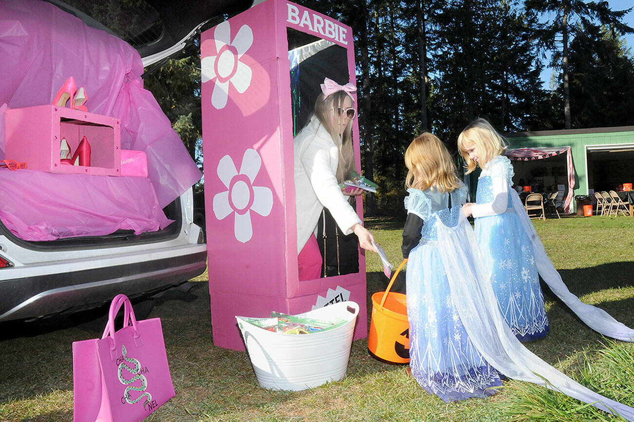 Janaye Birkland of Sequim takes on the persona of Barbie as she passes out treats to Sophie Van Proyen, 5, right, and Shelbie Van Proyen, both of Sequim, during Saturday’s Sequim Prairie Grange Fall Festival & Trunk or Treat at the grange hall near Carlsborg. The festival featured pumpkin carving, children’s games and treats handed out to costumed youngsters. (Keith Thorpe/Peninsula Daily News)