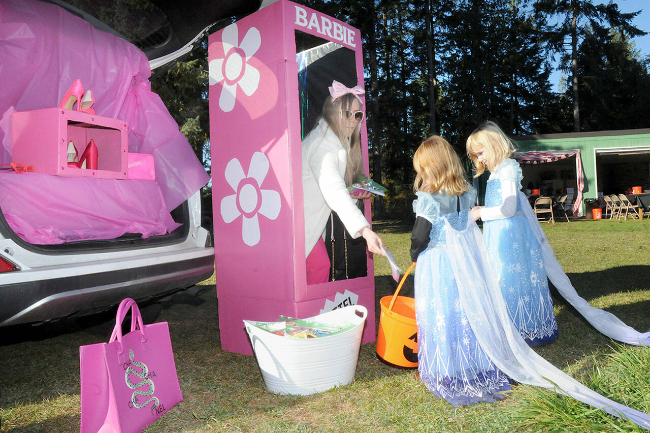 Janaye Birkland of Sequim takes on the persona of Barbie as she passes out treats to Sophie Van Proyen, 5, right, and Shelbie Van Proyen, both of Sequim, during Saturday’s Sequim Prairie Grange Fall Festival & Trunk or Treat at the grange hall near Carlsborg. The festival featured pumpkin carving, children’s games and treats handed out to costumed youngsters. (Keith Thorpe/Peninsula Daily News)