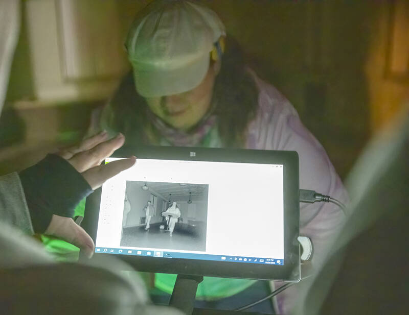 A paranormal fan looks at a monitor showing an image from a infrared camera set up in a room at the School House at Fort Worden State Park on Saturday night in the hopes of catching a ghostly image of a spirit passing through the room during a paranormal investigation as part of the Haunted Histories and Mysteries of Port Townsend weekend by the Port Townsend Main Street Association. (Steve Mullensky/for Peninsula Daily News)