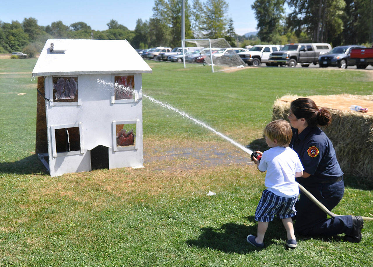 Plenty of activities will be offered at the Public Safety and Information Fair on Saturday in the Guy Cole Event Center. One activity will be similar to this event, pictured in August 2014, where Aidan Coonelly practices his skills with a fire hose with help from Emily Rodriguez. (Michael Dashiell/Olympic Peninsula News Group)