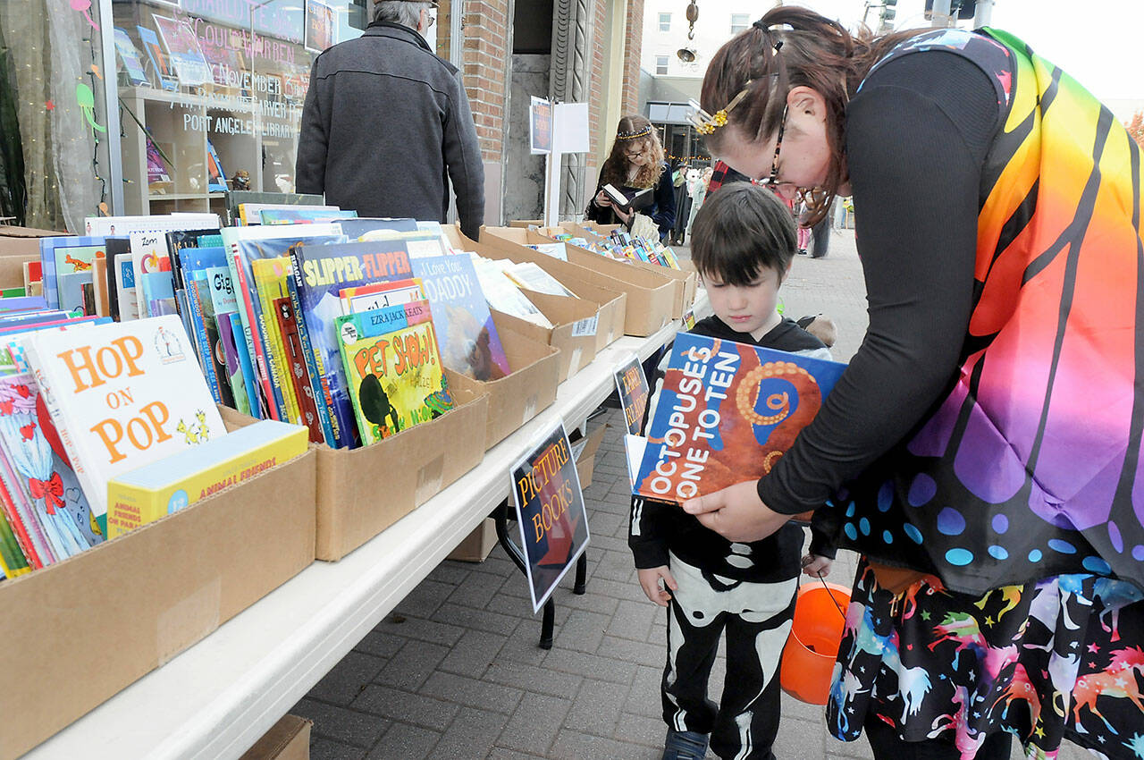 Dom Houk, 4, of Port Angeles looks over a free book with Bella Watson during Tuesday’s Halloween book giveaway in front of Port Book and News while trick or treating in downtown Port Angeles. (Keith Thorpe/Peninsula Daily News)
