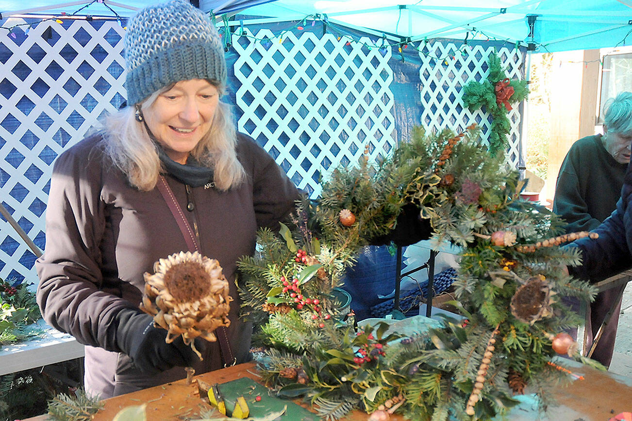 Glynda Ball of Sequim puts the finishing touches on a self-made wreath at a wreath-making station at Saturday’s Nature Mart at the Dungeness River Nature Center in Sequim. The event, a fundraiser for the nature center’s education programs, also featured a gift mart of hand-crafted, nature-related gifts, a bake sale and photo opportunities with the center’s taxidermic animals. (Keith Thorpe/Peninsula Daily News)