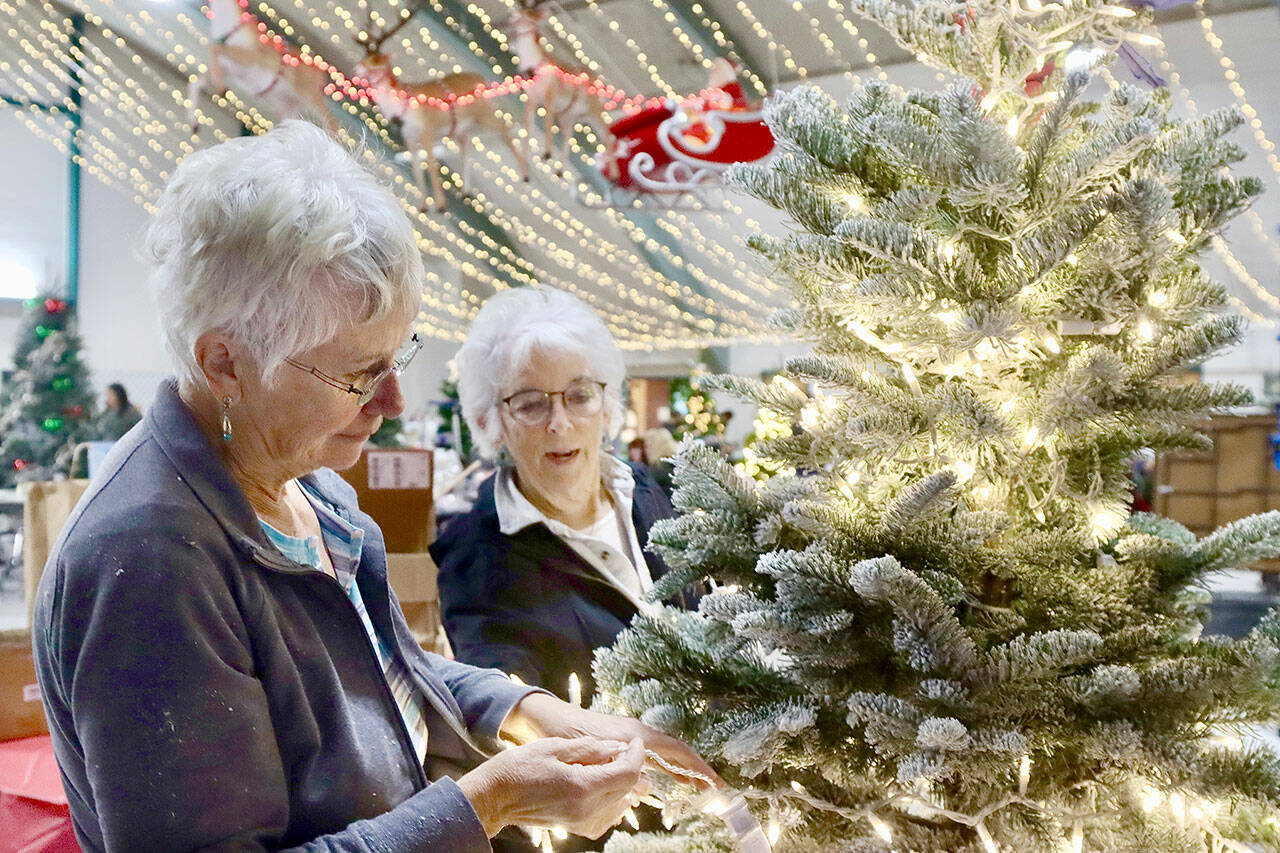 Sue Chance, left, and Betsy Schultz decorate their tree called, “Draped With Honor, Respect and Remembrance” for the 33rd annual Festival of Trees this coming weekend. (Dave Logan/for Peninsula Daily News)