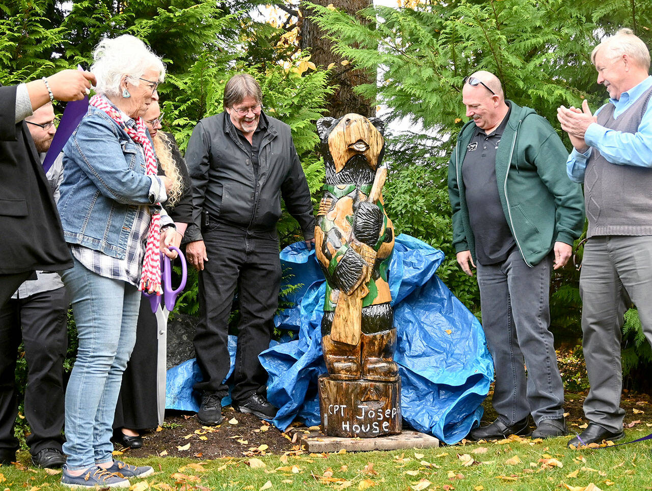 Betsy Reed Schultz (far left), founder of Captain Joseph House, gets a look at a carved bear donated by Bret Wirta’s Black Bear Diner and Holiday Inn & Suites last week at the Port Angeles facility. (Michael Dashiell/Olympic Peninsula News Group)