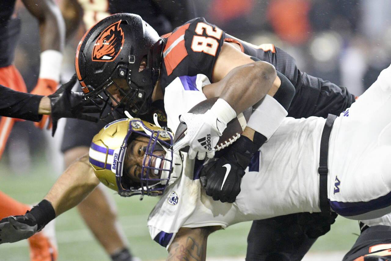Washington running back Dillon Johnson is brought down by Oregon State linebacker Cory Stover (82) during the second half of an NCAA college football game Saturday, Nov. 18, 2023, in Corvallis, Ore. (AP Photo/Mark Ylen)