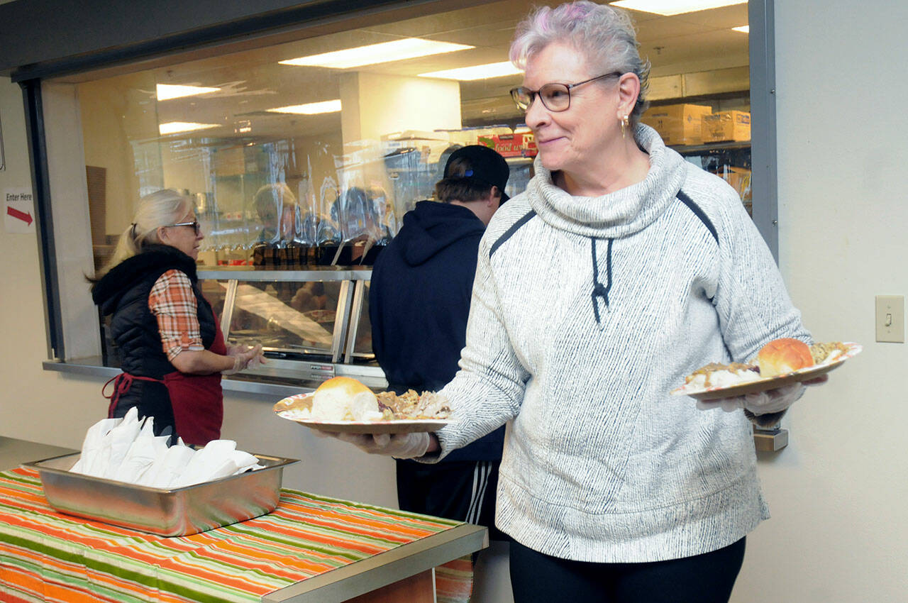 Volunteer Merry Svenson of Port Angeles carries plates of turkey and fixings to be served to hungry visitors during Wednesday’s annual pre-Thanksgiving lunch at the Salvation Army Social Service Center in Port Angeles. (Keith Thorpe/Peninsula Daily News)