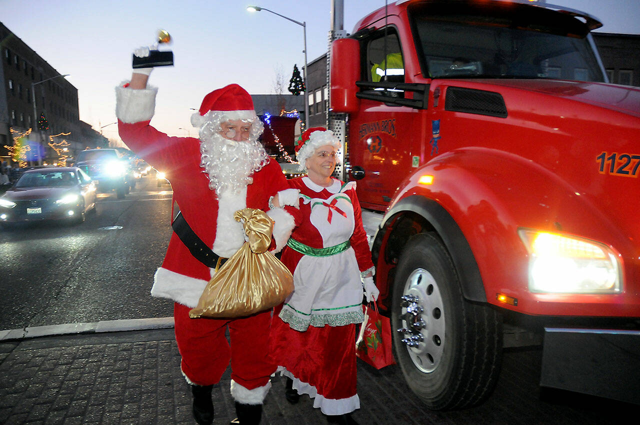 Santa and Mrs. Claus, portrayed by Bob Nicholls of White Crane Martial Arts and his wife, Kathy Nicholls, arrive in downtown Port Angeles from atop a truck provided by Herman Brothers Logging & Construction during Saturday’s Port Angeles Hometown Holidays celebration on Laurel Street and at the Conrad Dyar Memorial Fountain. Besides a visit from the Jolly Old Elf, the event featured music and entertainment, food and lighting of the downtown Christmas tree. (Keith Thorpe/Peninsula Daily News)