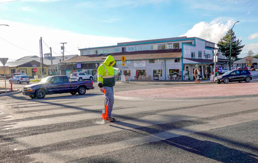Rich Foutch of Active Construction, Inc., in Tacoma paints a line on the roadway at the new roundabout at Kearney Street and state Highway 20 for the placement of temporary stripes in a pedestrian crosswalk on Monday in Port Townsend. The temperatures have to be in the mid-50s to install permanent striping, he said. (Steve Mullensky/for Peninsula Daily News)
