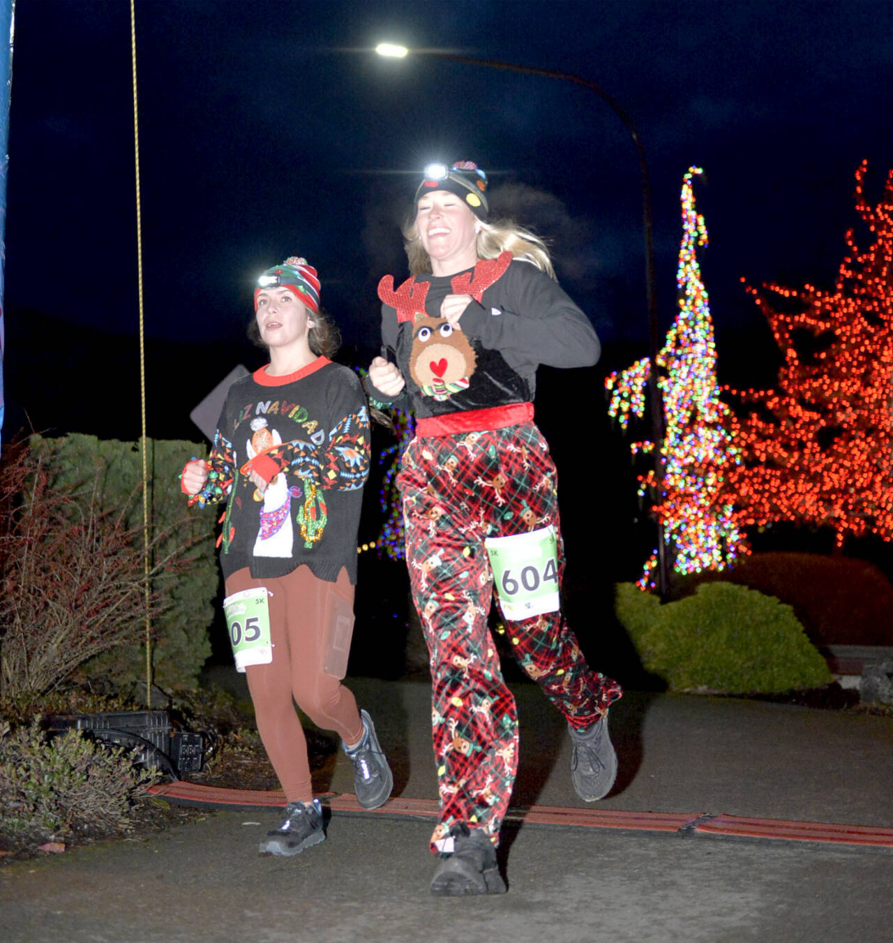 Sami Nolan, left, and Chelsea Pluard, both of Port Angeles, finish the 5K in the 2022 edition of the Jamestown S’Klallam Glow Run in Blyn. The race returns Saturday afternoon and evening. (Run the Peninsula)