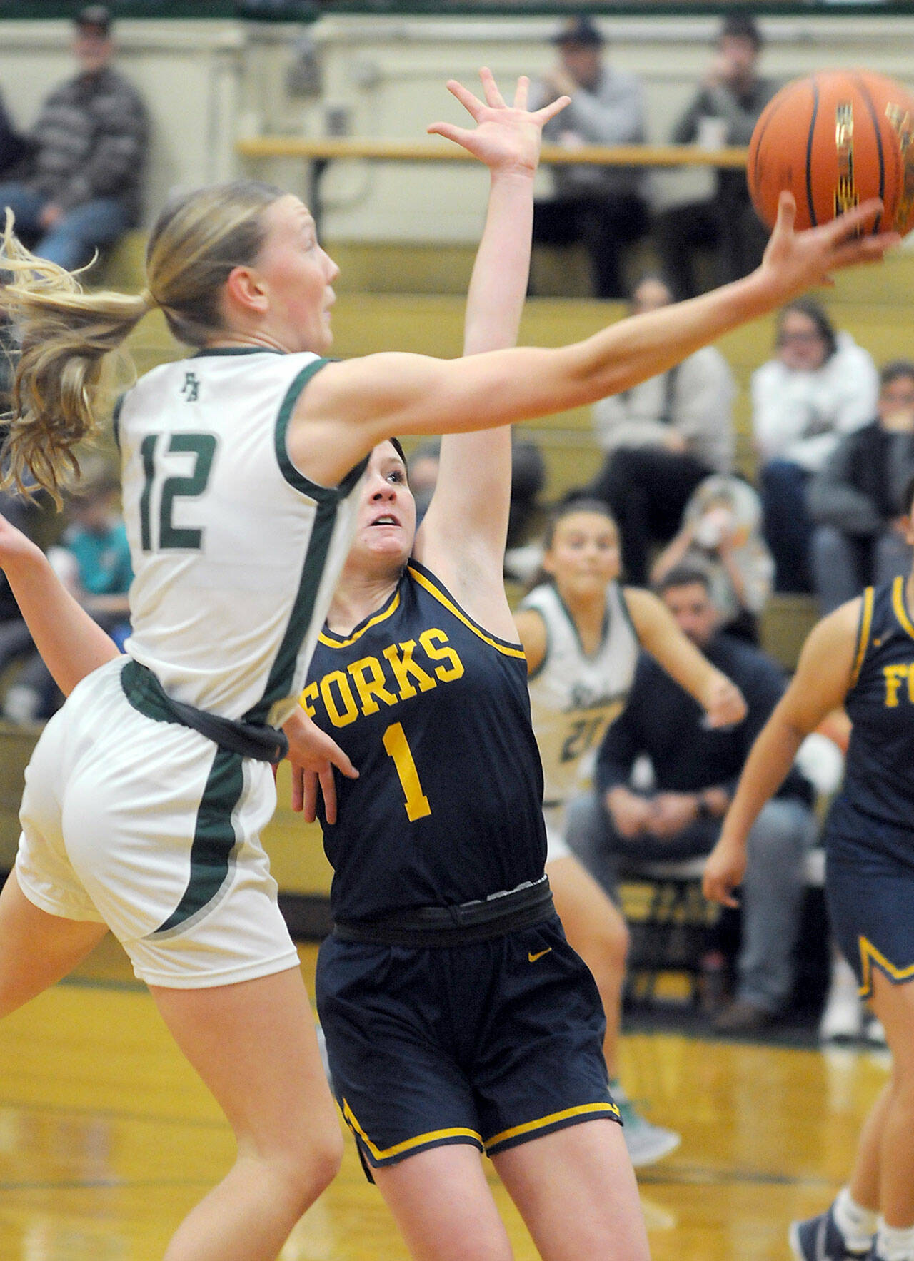 Port Angeles’ Izzy Felton, front, looks for the layup as Forks’ Bailey Johnson defends the lane on Tuesday night in Port Angeles. (Keith Thorpe/Peninsula Daily News)