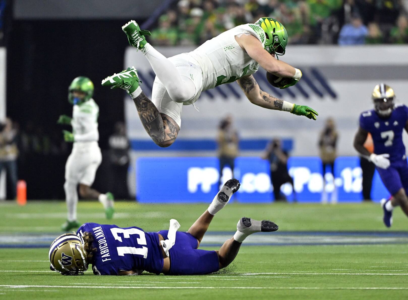 Oregon tight end Terrance Ferguson (3) is tripped up by Washington cornerback Kamren Fabiculanan (13) during the first half of the Pac-12 championship NCAA college football game Friday, Dec. 1, 2023, in Las Vegas. (AP Photo/David Becker)