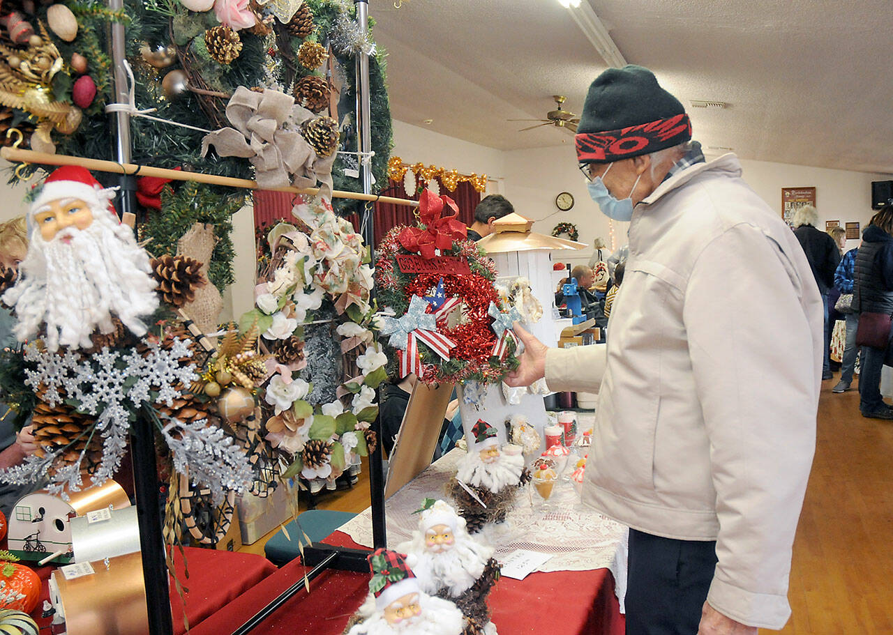 Arthur Seward of Sequim examines a display of handmade wreaths created by Sequim-based The Hitching Post during Saturday’s Holiday Craft Fair at the Sequim Prairie Grange near Carlsborg. The fair featured a variety of holiday-themed crafts and gifts made by local artisans, as well as lunch prepared by grange members. (Keith Thorpe/Peninsula Daily News)