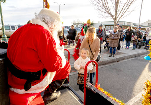 Dylan Kinney, 4, is introduced to Santa by her gran Debbie Hinton, both from Port Townsend, as Santa greeted kids on Saturday in downtown Port Townsend. (Steve Mullensky/for Peninsula Daily News)