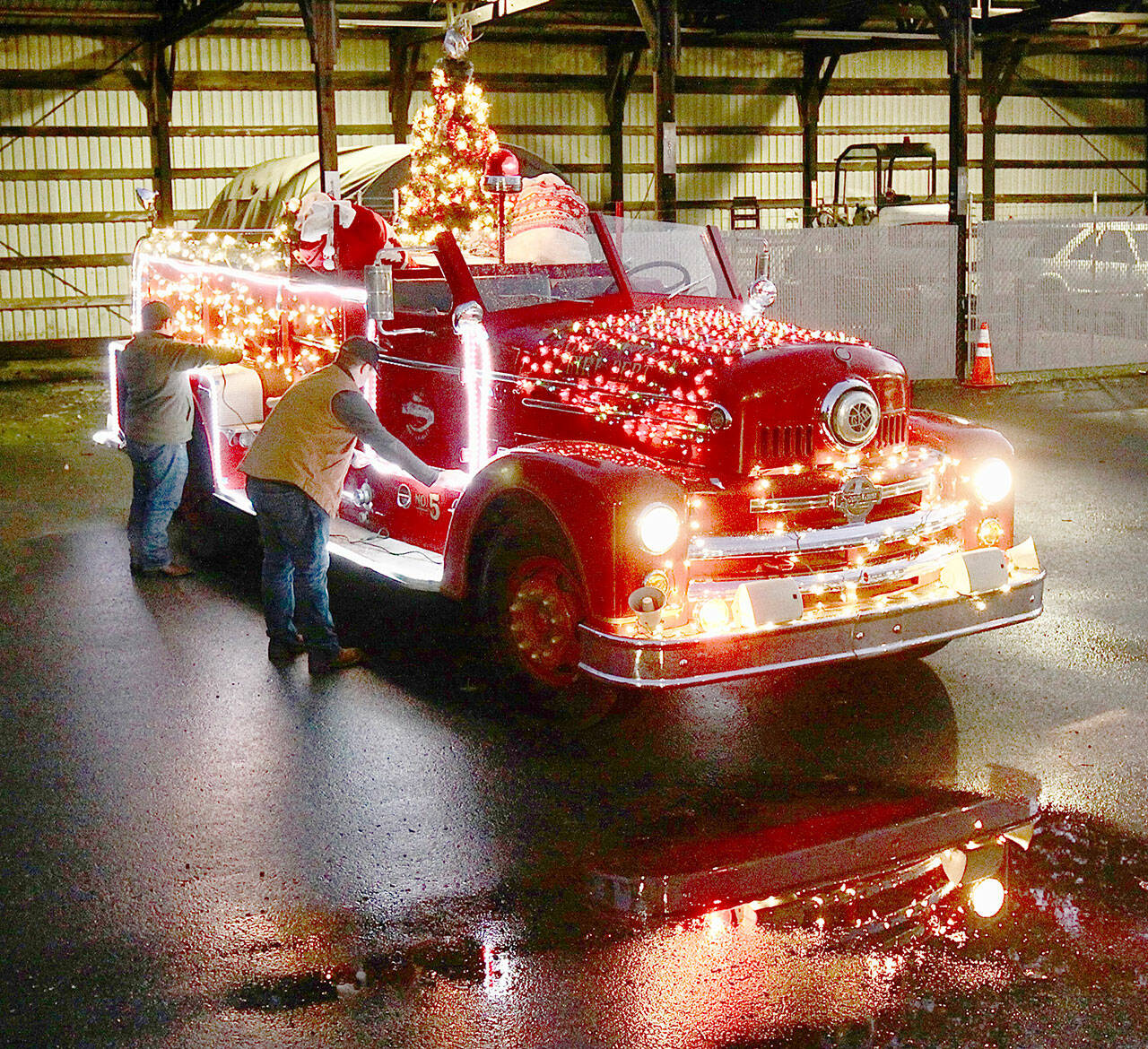 Tyler Gage and Adam DeFilippo decorate the 1956 Seagrave fire engine in 2022. (Dave Logan/For Peninsula Daily News)