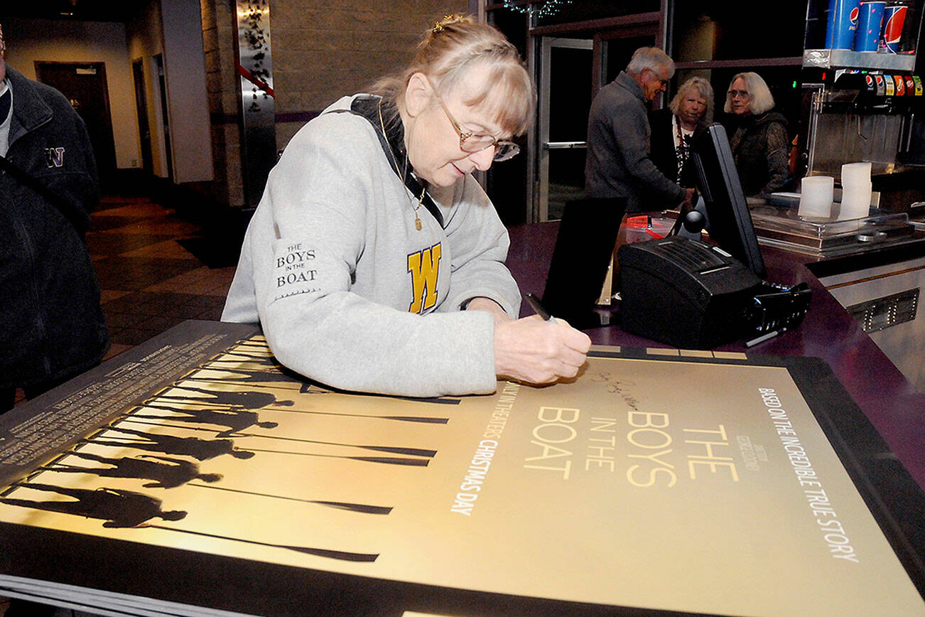 Judy Willman, daughter of University of Washington rowing team member Joe Rantz, signs a movie poster for the movie “The Boys in the Boat,” a tribute to the team’s rise to winning a gold medal in the 1936 Olympics. (Keith Thorpe/Peninsula Daily News)