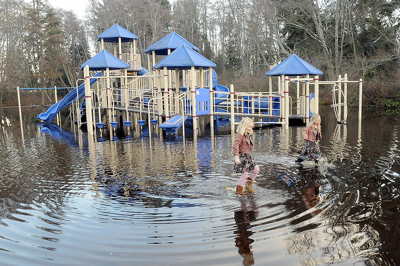 Josie Atkisson, left, and her friend, Danielle Romano, both 6 of Port Angeles, wade through a flooded area around the play equipment at Shane Park in Port Angeles on Wednesday. (Keith Thorpe/Peninsula Daily News)