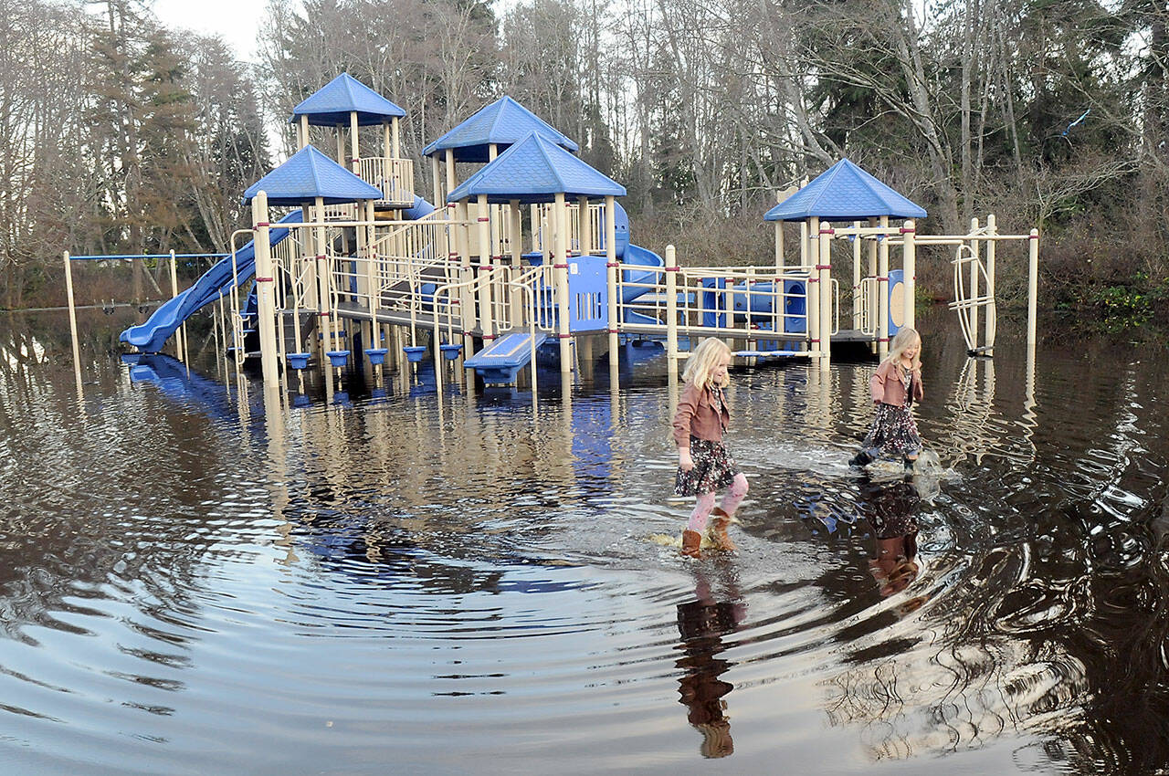 Josie Atkisson, left, and her friend, Danielle Romano, both 6 of Port Angeles, wade through a flooded area around the play equipment at Shane Park in Port Angeles on Wednesday. (Keith Thorpe/Peninsula Daily News)