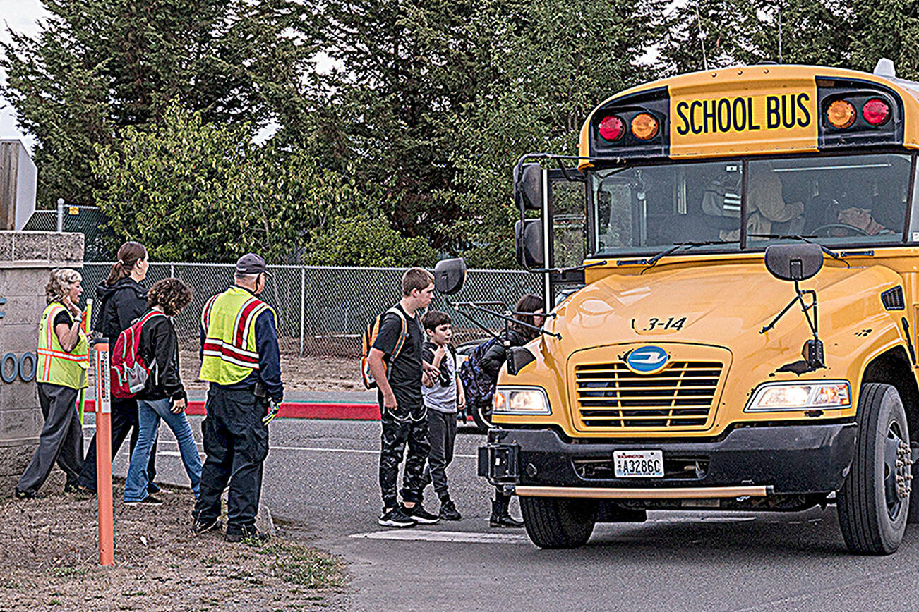 Community Emergency Response Team (CERT) members help students ride the bus in September while helping direct traffic for parents at drop-off/pick-up for the K-2, 3-5 reconfiguration of Greywolf and Helen Haller elementary schools. Sequim School District officials have started conversations to consider changing bus routes to improve attendance and behavior, among other things. (Michael Dashiell/Olympic Peninsula News Group)