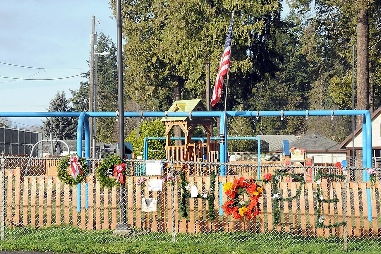 Wreathes, personal notes and flowers adorn the fence outside the Dream Playground at Erickson Playfield in Port Angeles on Tuesday after much of the playground was destroyed by fire last week. (Keith Thorpe/Peninsula Daily News)