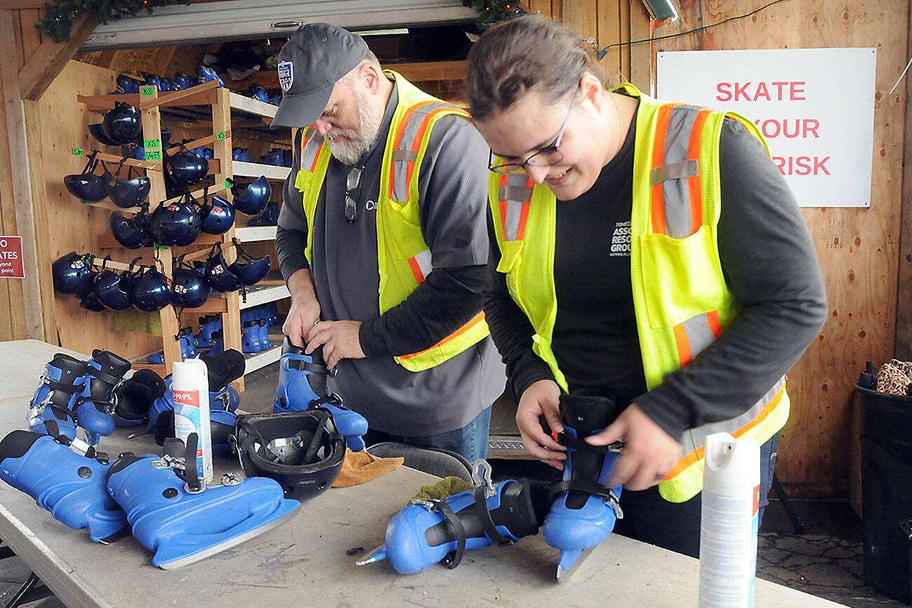 KEITH THORPE/PENINSULA DAILY NEWS
Port Angeles Winter Ice Village volunteers Rich Johnson, left, and Sarah Fixter check in used ice skates on a busy Friday afternoon skate session.