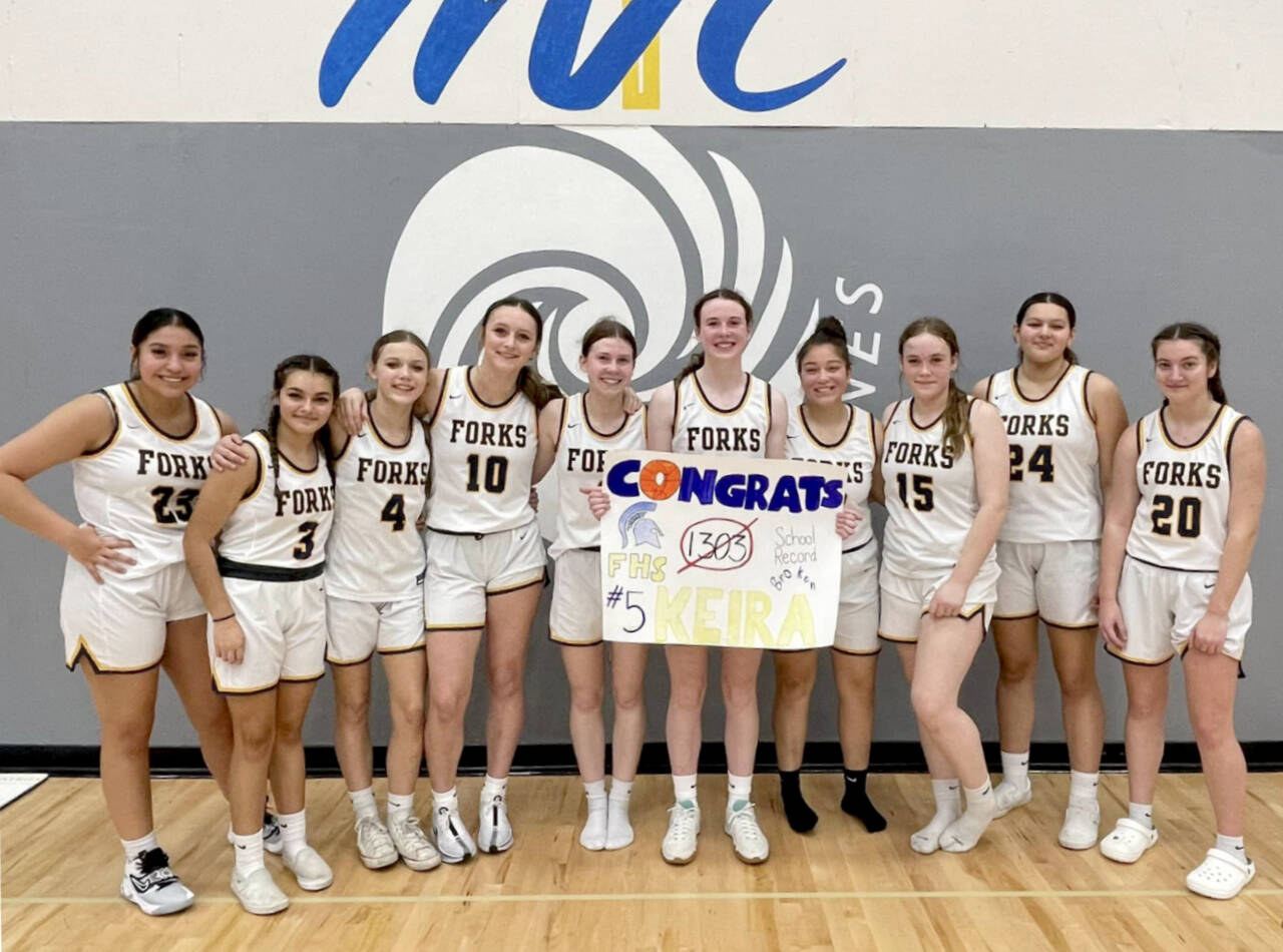 Forks basketball player Keira Johnson (holding sign) celebrates her career school scoring record with her teammates at a game at Mount Vernon Christian High School in Mount Vernon on Friday. (Courtesy photo)