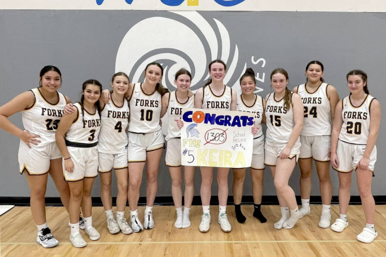 Forks basketball player Keira Johnson (holding sign) celebrates her career school scoring record with her teammates at a game at Mount Vernon Christian High School in Mount Vernon on Friday. (Courtesy photo)