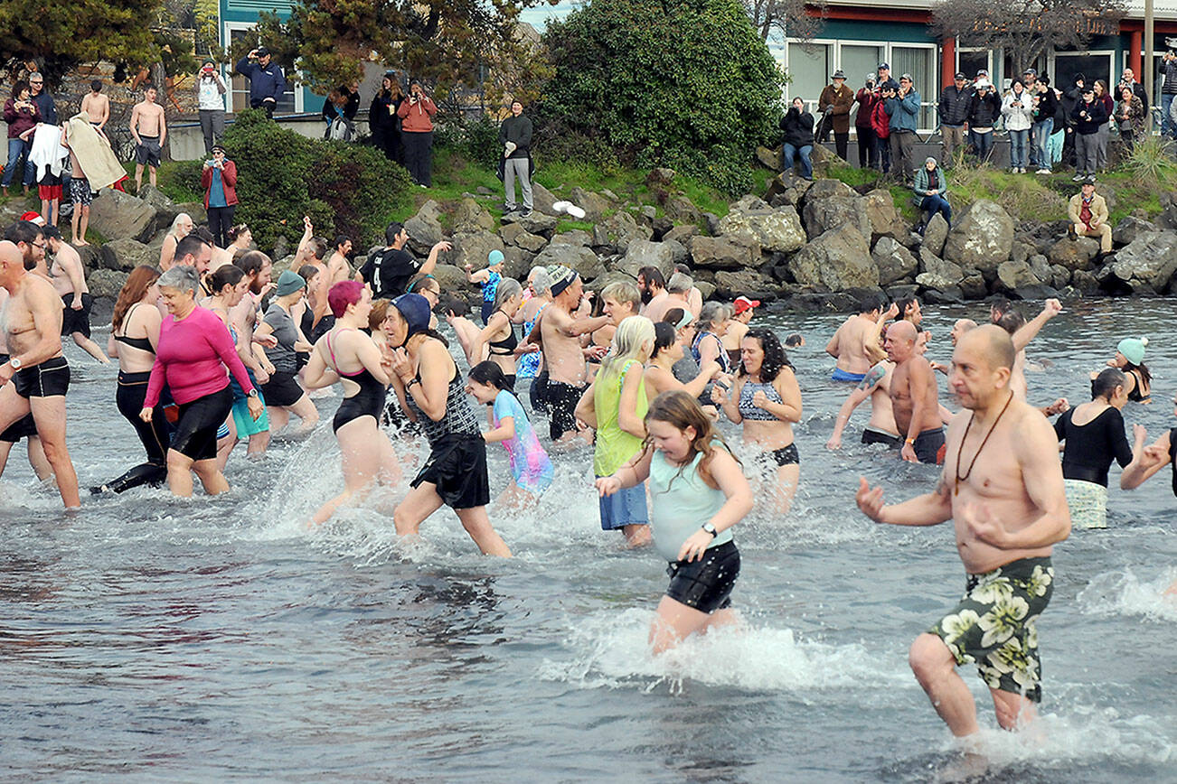 Participants in the New Year’s Day polar bear dip in Port Angeles run in and out of the chilly water of Port Angeles Harbor at Hollywood Beach as onlookers watch from the shore on Monday. More than 100 dippers took part in the annual ritual, which served as a fundraiser for Volunteer Hospice of Clallam County. (Keith Thorpe/Peninsula Daily News)