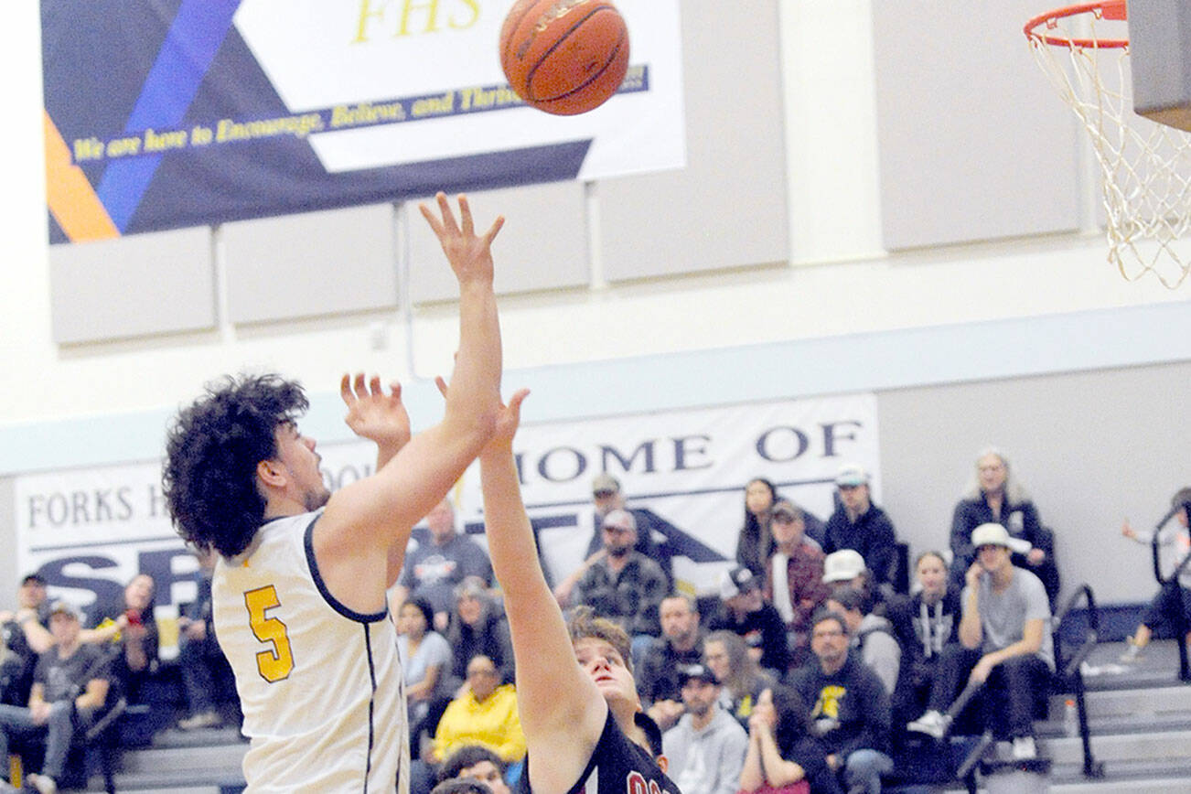 Forks’ Landin Davis puts up a shot over Ocosta’s Kayden Turner while Forks’ Brody Lausche looks on. (Lonnie Archibald/for Peninsula Daily News)