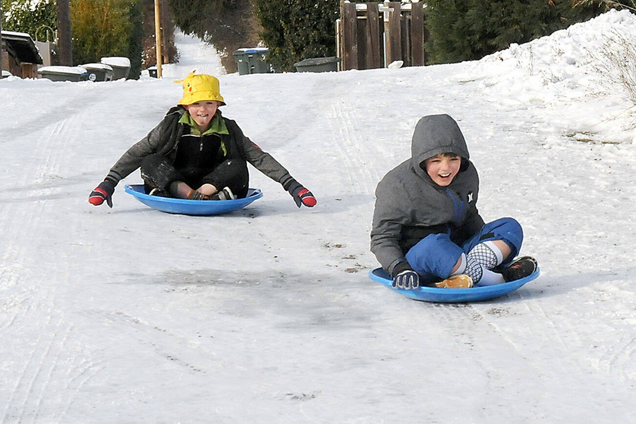 Cameron Torres, 8, left, and his brother, Steven Torres, 9, slide their way down a frozen alley behind their home near 11th and C streets in Port Angeles on Saturday. The youngsters braved temperatures in the 20s and wind chills in the teens in pursuit of some gravity-assisted entertainment. (Keith Thorpe/Peninsula Daily News)