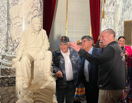 Nisqually Tribal Chairman Willie Frank III, right, discusses the newly designed statue mockup of his father, Billy Frank Jr., with other attendees at Wednesday’s unveiling. A full-scale, bronze statue of Billy Frank Jr. will be placed in the U.S. Capitol’s National Statuary Hall in Washington, D.C., next year. (Laurel Demkovich/Washington State Standard)