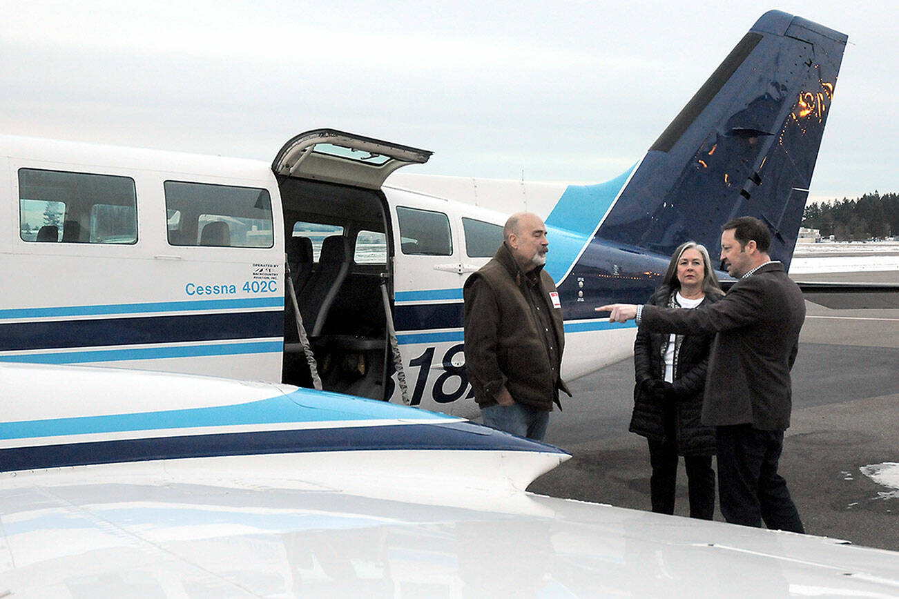 KEITH THORPE/PENINSULA DAILY NEWS
Clint Ostler, president of Dash Air Shuttle, right, points out features of the Cessna 402C aircraft to Peter Metz, left, and Kim Reynolds, both of Port Angeles, during an open house for the air service on Tuesday at William R. Fairchild International Airport in Port Angeles.