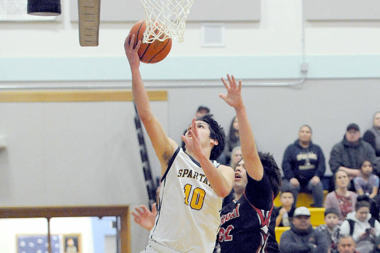 Forks’ Dylan Micheau (10) scores over Neah Bay’s Mathias Greene Monday evening in Forks. (Lonnie Archibald/for Peninsula Daily News)