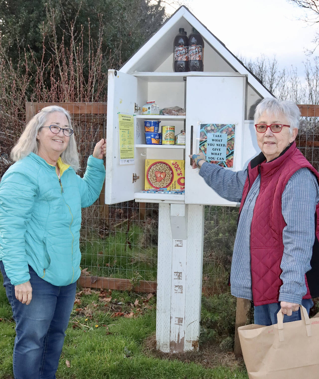 Martha Bell, left, and Nancy Jacobson put new donations into the Little Free Pantry box at 316 S. Cherry St. that is sponsored by First Presbyterian Church in Port Angeles. (Dave Logan/For Peninsula Daily News)