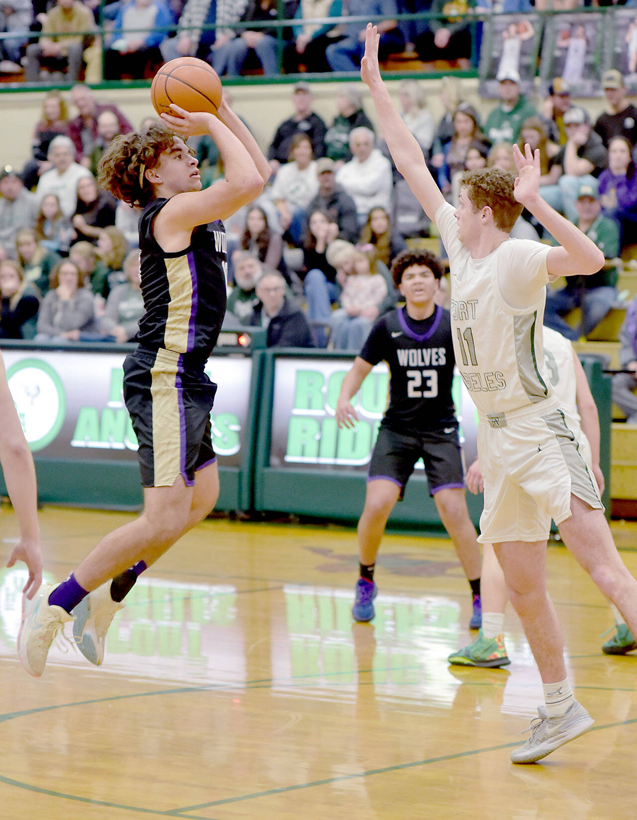 KEITH THORPE/PENINSULA DAILY NEWS Sequim’s Lars Wiker, left, takes aim at the rim as Port Angeles’ Dallas Dunning, right, tries to block on Tuesday in Port Angeles.