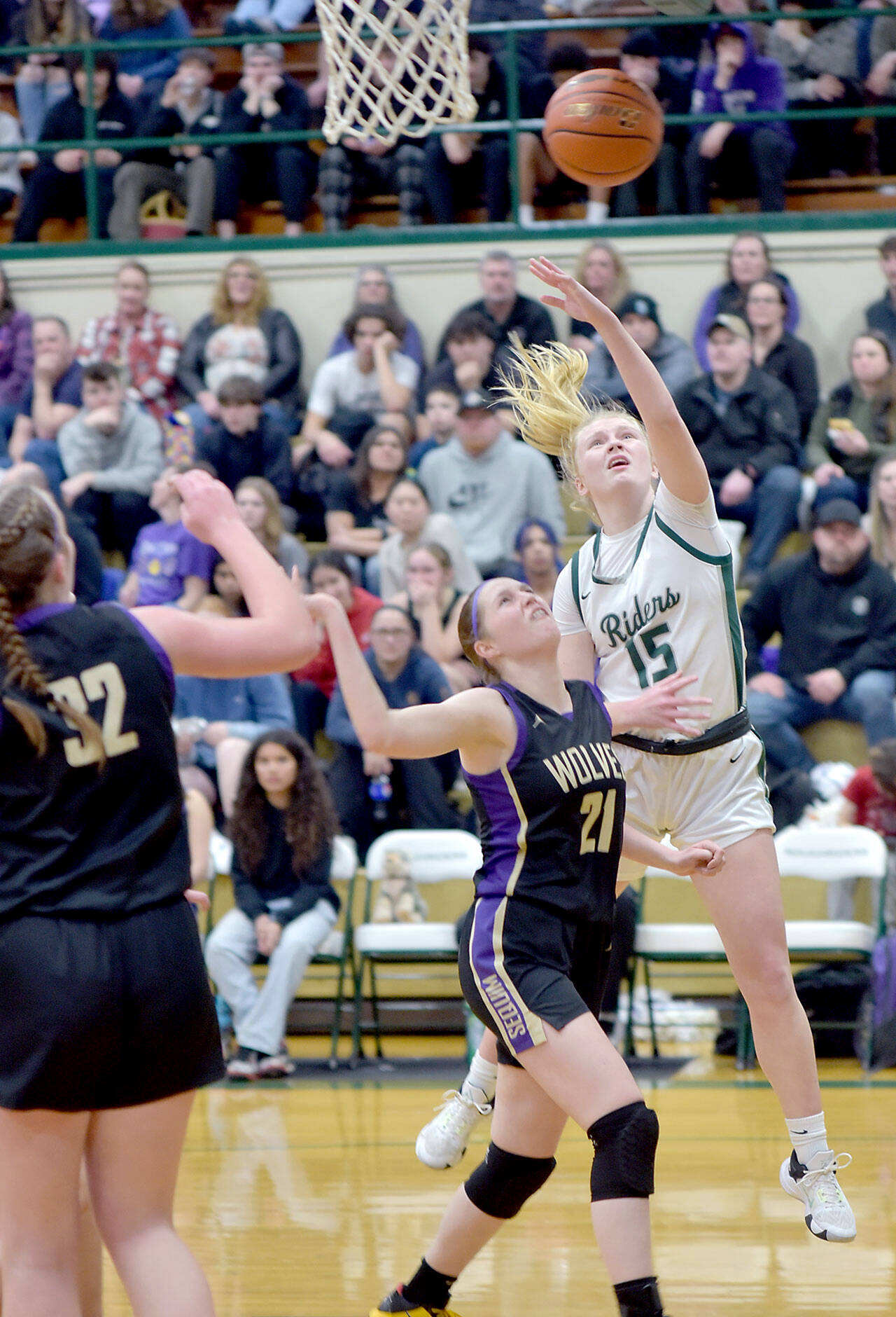 Port Angeles’ Paige Mason, right, puts up the ball over the head of Sequim’s Libby Turella as Sequim’s Hailey Wagner looks on at left on Tuesday at Port Angeles High School. Mason led the Roughriders with 26 points to help Port Angeles win 74-46 and clinch an Olympic League championship and a No. 1 seed for the playoffs. (KEITH THORPE/PENINSULA DAILY NEWS)