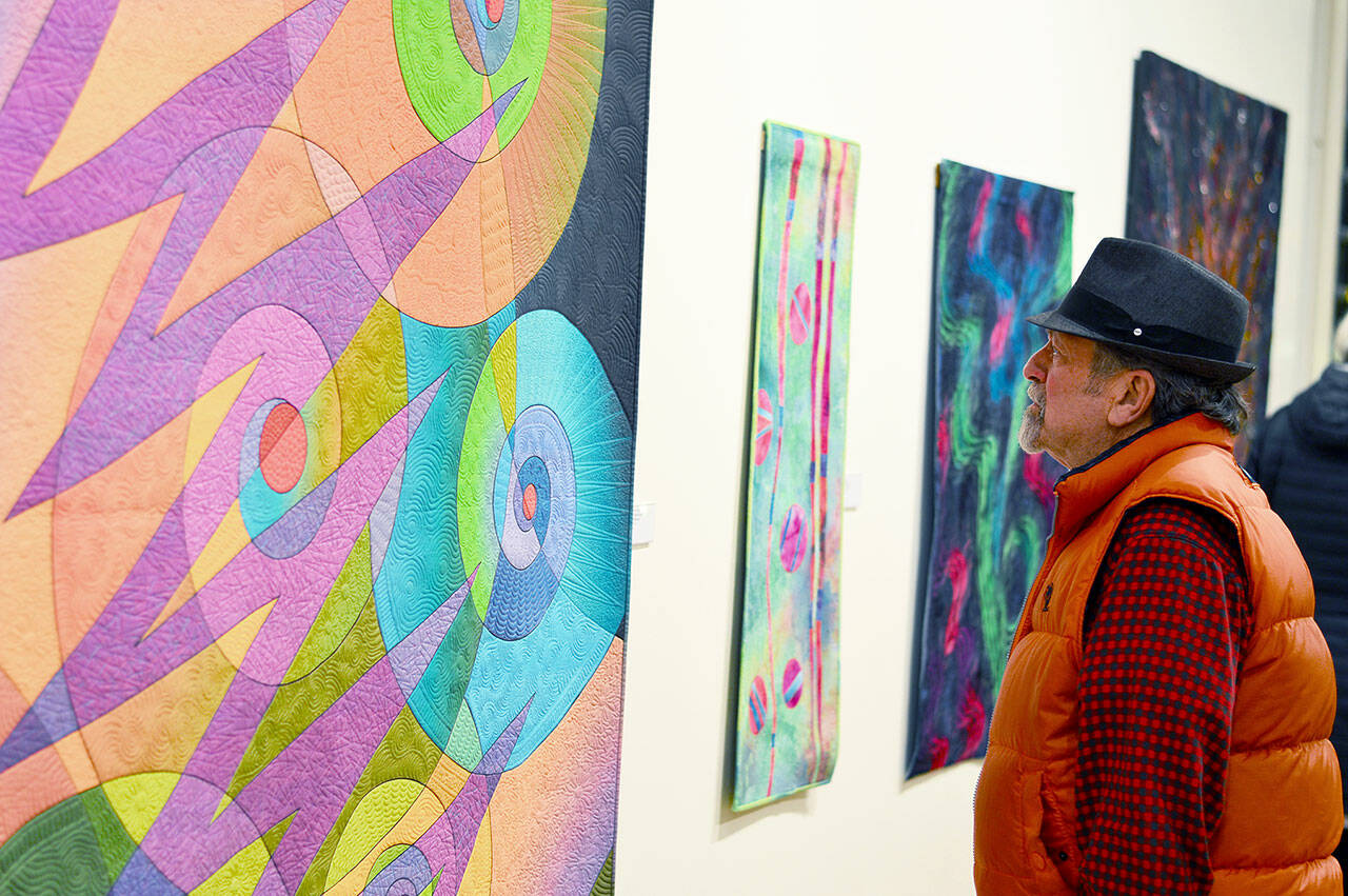 Richard Coletta of Port Townsend admires Caryl Fallert-Gentry’s quilt titled “Electric Snails,” part of the “Burst of Color” exhibit at Jeanette Best Gallery. (Richard Coletta/Northwind Art)