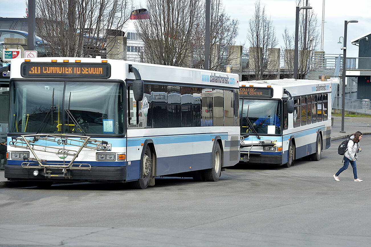 A pair of Clallam Transit buses sit at The Gateway Transit Center in Port Angeles in preparation for their fixed-route runs on Thursday. (Keith Thorpe/Peninsula Daily News)