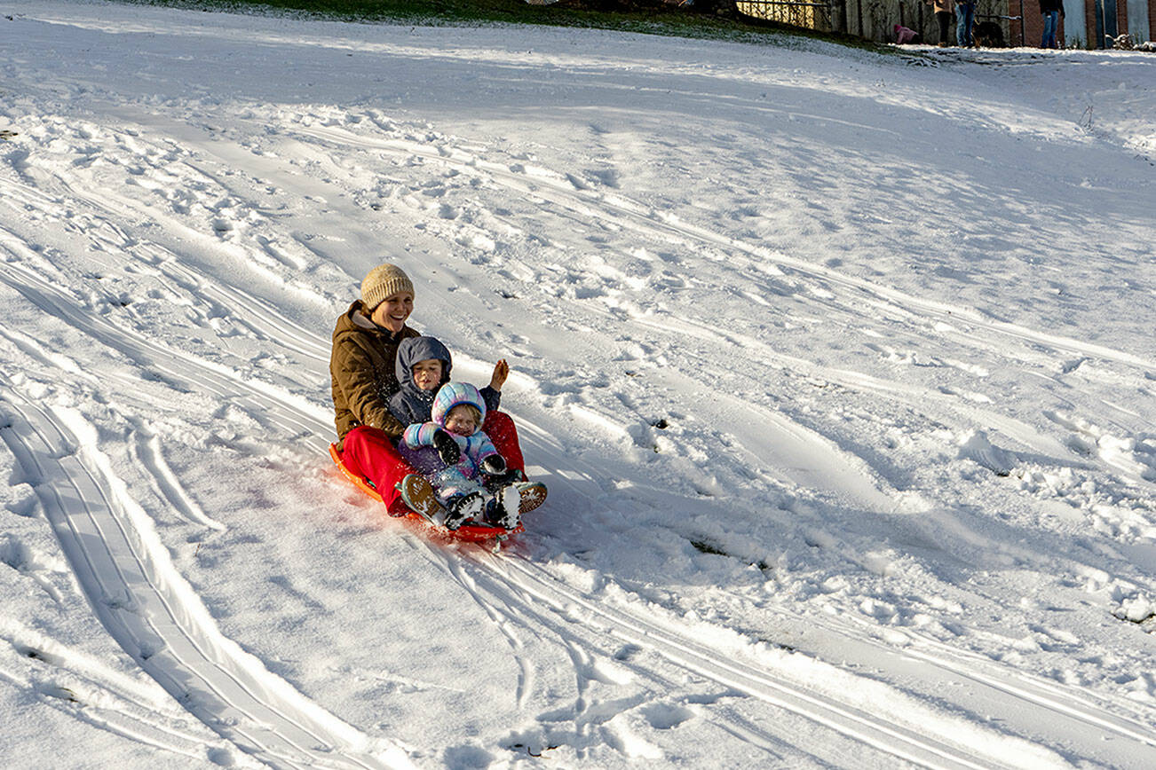 Lena Curtis guides a snow sled with her two children, Lucien Williams, 4 1/2, and Millie, 2, all from Port Townsend, down a snow hill at Port Townsend High School on Tuesday. An overnight storm passed through but not before depositing about 3 inches of soft powder, which melted rapidly as the day warmed. The blast of snowfall was largely confined to the area around Port Townsend and Port Hadlock overnight into Tuesday morning on the North Olympic Peninsula. Another weather system was coming in on Tuesday afternoon and is expected to drop rain in the lowlands and snow in the mountains on Wednesday and early Thursday, according to meteorologist Jacob DeFlitch with the National Weather Service in Seattle. (Steve Mullensky/for Peninsula Daily News)
