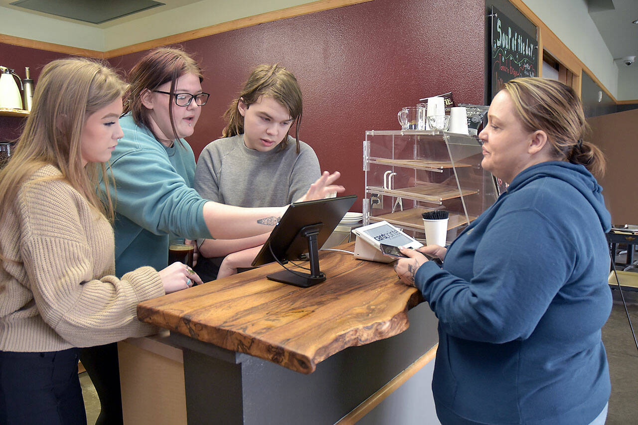 Coffee customer Lauren Wright of Port Angeles, right, gets assistance at the counter from Career and Technical Education program students, from left, Jordis Vance, 17, Rayin Blewett, 18, and Maple Romberg, 16, on Friday’s opening day of the Wildcat Cafe at Lincoln Center in Port Angeles. (KEITH THORPE/PENINSULA DAILY NEWS)