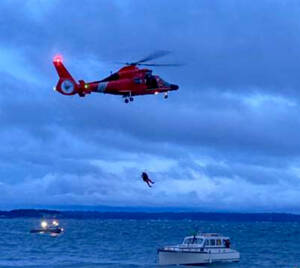 A Coast Guard helicopter lowers a swimmer on Saturday to a vessel that was on the rocks off Marrowstone Island. (East Jefferson Fire Rescue)