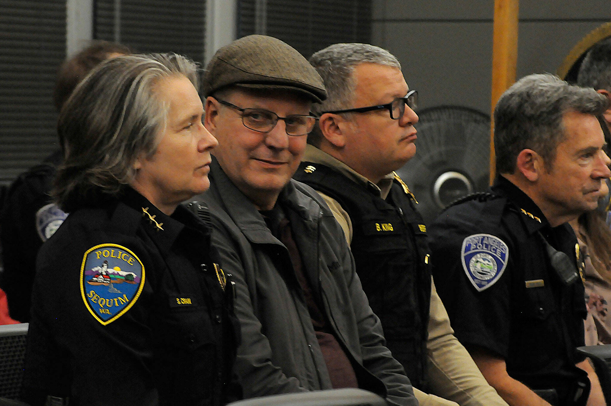 Matthew Nash/ Olympic Peninsula News Group
Sequim Police Chief Sheri Crain listens to a proclamation at the Feb. 26 Sequim city council meeting as her husband Pat smiles with pride in her during the ceremony. Next to Pat is Clallam County Sheriff Brian King and, to his right, Port Angeles Police Chief Brian Smith.