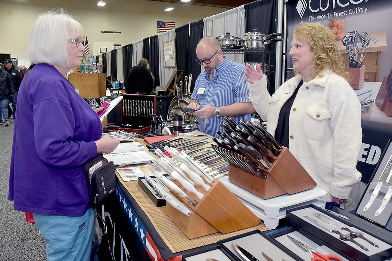 Brenda Close of Port Angeles, left, talks with Cutco Cutlery representative Allison Gilman, right, as Matt Makowicz of Cutco uses his calculator at the company’s booth at the 39th annual Clallam County Home and Lifestyle Show on Saturday at Port Angeles High School. The two-day event, hosted by KONP Radio, featured 120 exhibitor booths showcasing a wide variety of goods and services with primary sponsorship by Clallam County Public Utilities District, Lumber Traders and Leitz Farm Supply. (Keith Thorpe/Peninsula Daily News)