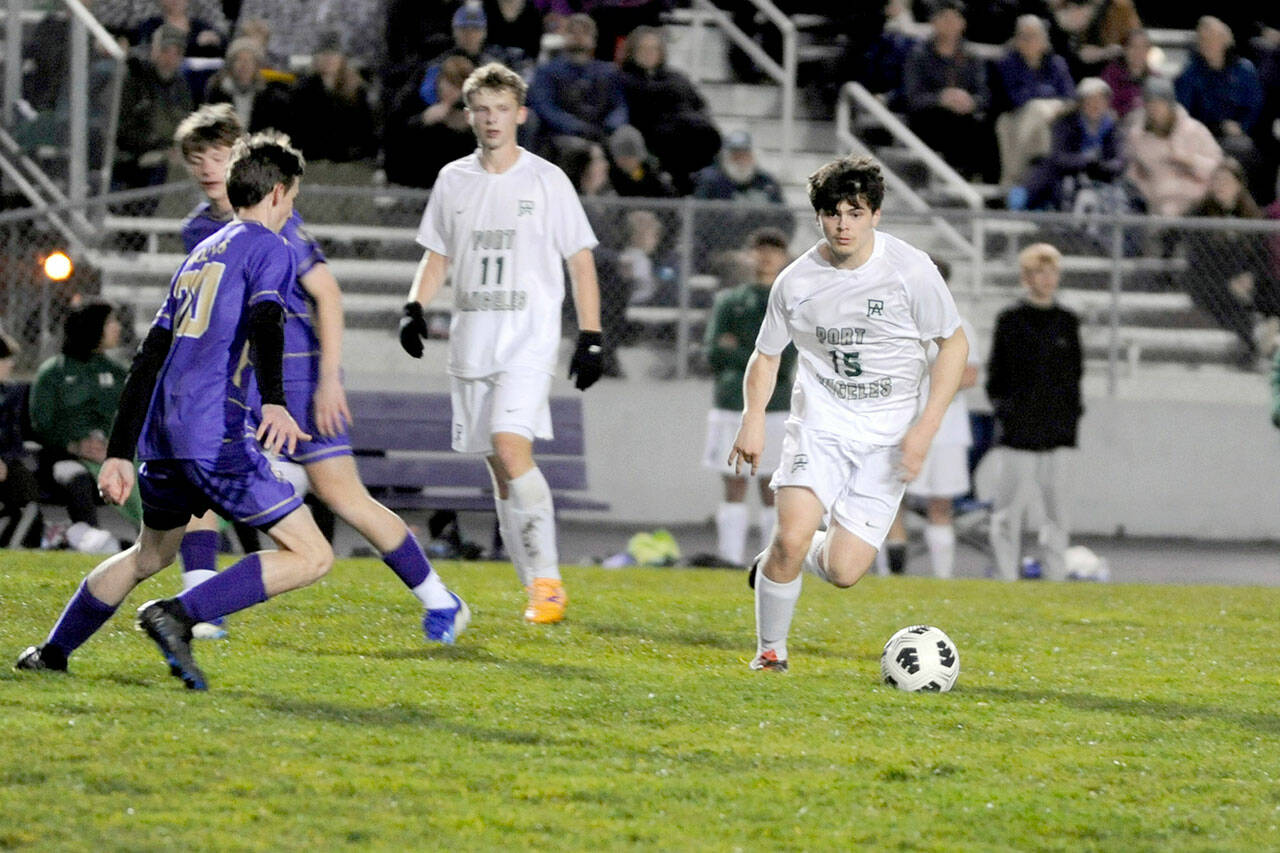 Matthew Nash/for Olympic Peninsula News Group Port Angeles’ A.J. Martinez dribbles the ball upfield while defended by Sequim’s Colton Wagner during the Wolves’ 4-2 win Thursday night.