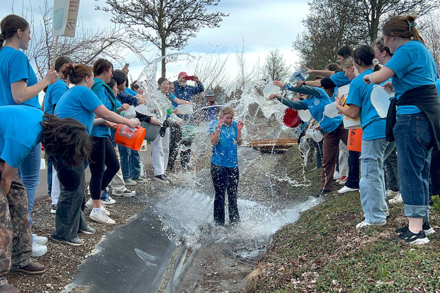 As is tradition at the end of the Walk for Water, Interact Club members douse the president — this year Krista Charters — in Sequim’s original irrigation ditch by Sequim Middle School. Charters said carrying two large buckets of water 2 miles was harder than she thought it’d be. (Matthew Nash/Olympic Peninsula News Group)