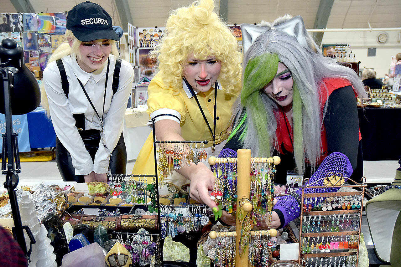 Convention attendees, from left, Kiera Woodward, Madison Peterson and Juliette Burnette, all of Port Angeles, examine displays of jewelry, earrings and crystals at a display table operated by Dragon Den Studios of Sequim at Squatchcon on Friday at Vern Burton Community Center in Port Angeles. The four-day festival, dedicated to gaming, culture and cosplay, continues today at Vern Burton with a vendor market, workshops and meetups. (Keith Thorpe/Peninsula Daily News)