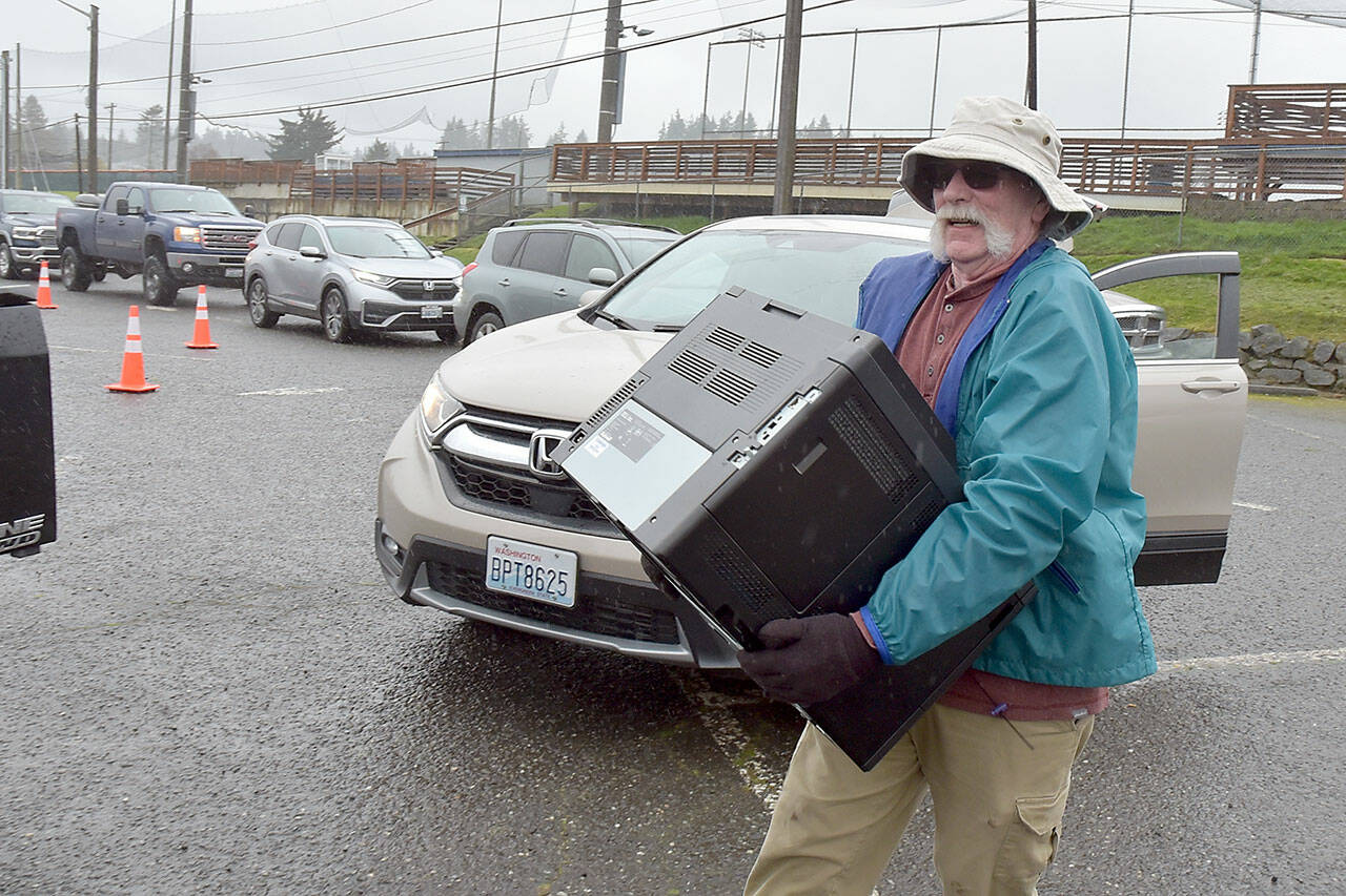 Bobby Doisher, a prospective member of the Olympic Kiwanis Club, carries a discarded printer to a waiting truck to be taken away for recycling as a line of cars wait to drop off unwanted electronic equipment during the club’s electronics recycling event on Saturday in the parking lot of Port Angeles Civic Field. The club, in partnership with SBK Recycling, collected hundreds of pounds of old computers, televisions, printers and other equipment as vehicles lined up for blocks along nearby Race Street to dispose of castoff electronics. Proceeds from the event were to benefit Kiwanis service programs. (Keith Thorpe/Peninsula Daily News)