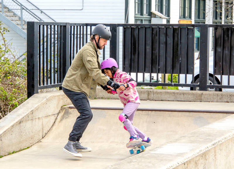 Dane Schoonover of Port Townsend helps his daughter Lyra, 8, learn how to skateboard at the Port Townsend Skateboard Park on Monday. (Steve Mullensky/for Peninsula Daily News)