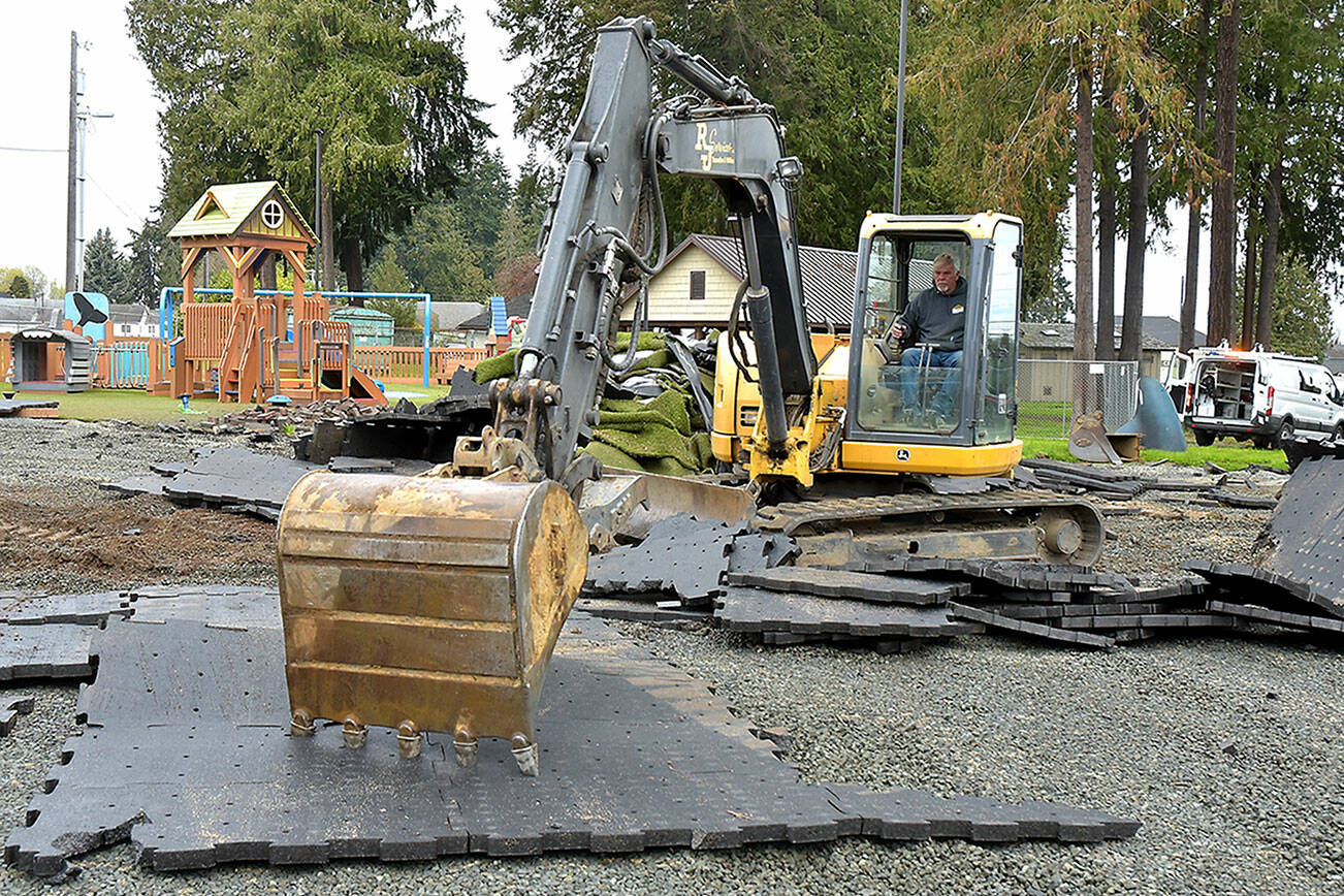 Kelly Couthlin of Port Angeles-based RJ Services Inc. uses an excavator to remove damaged surface padding tiles at the Dream Playground at Erickson Playfield in Port Angeles on Thursday. Surface removal paves the way for rebuilding the playground, currently scheduled as a volunteer community effort on May 15-19. A large portion of the playground was destroyed in an arson fire on Dec. 20. (Keith Thorpe/Peninsula Daily News)