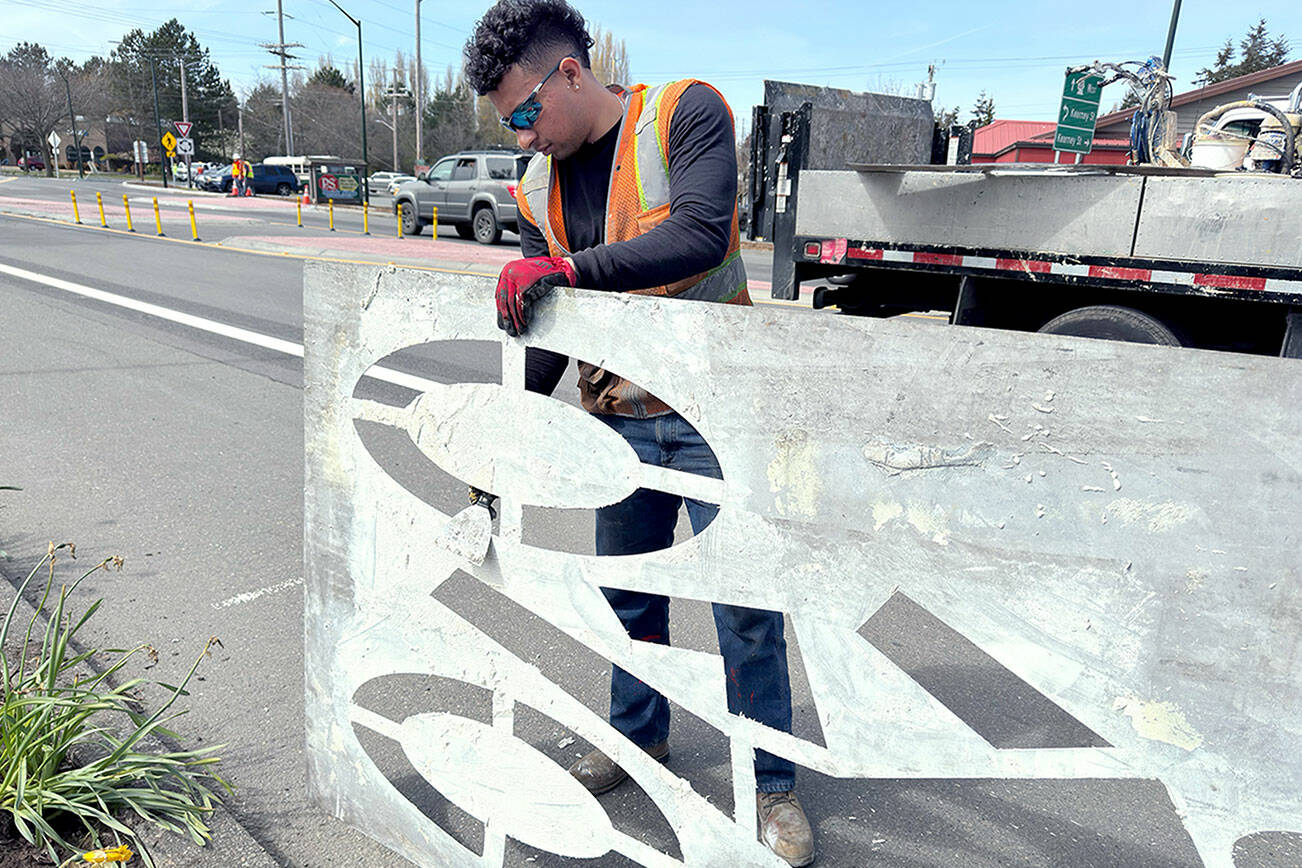 Fernando Cruz of Auburn, an employee of Specialized Pavement Marking in Pacific, cleans off a sign he used to paint a bicycle lane on Sims Way and Kearney Street, the site of the new roundabout. The workers needed at least two days of 47 degrees or above in order to paint the pedestrian crosswalks and other necessary markings. (Steve Mullensky/for Peninsula Daily News)