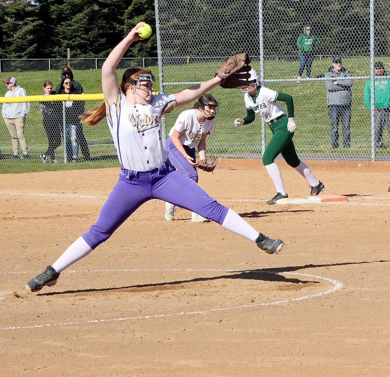 Dave Logan/for Peninsula Daily News
Sequim pitcher Nevaeh Owens delivers to the plate while Port Angeles baserunner first Lexie Smith gets ready to take off. Sequim first baseman Rylie Doig also in on the play as the No. 1-ranked Roughriders won 14-2.